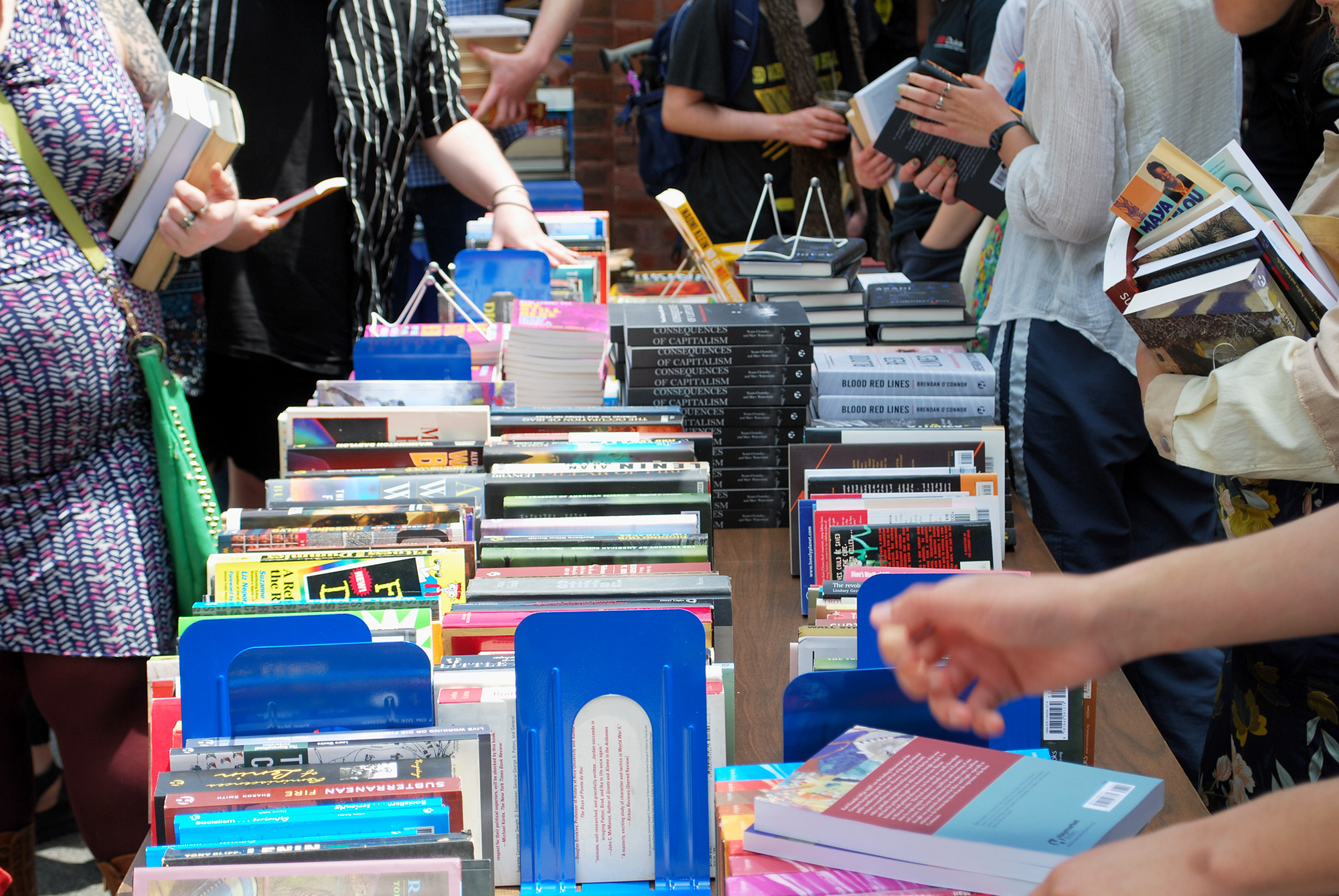 A large table of Haymarket books with people browsing.