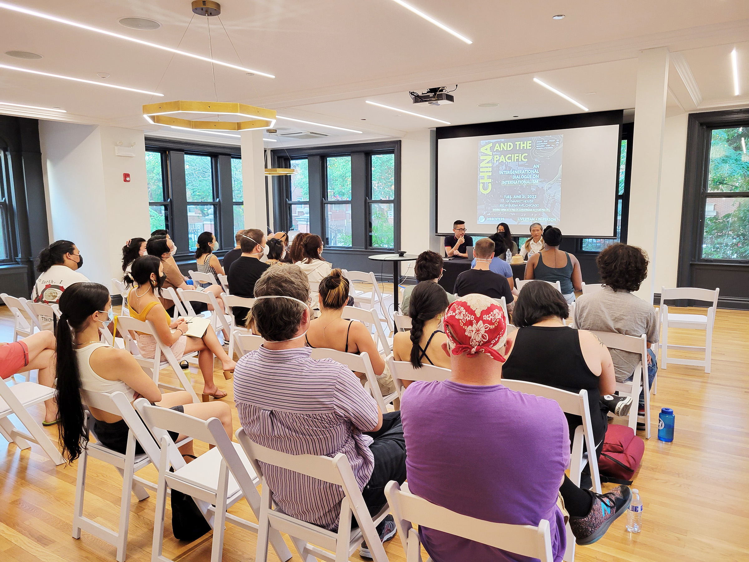 A panel of speakers gives a presentation to an audience.