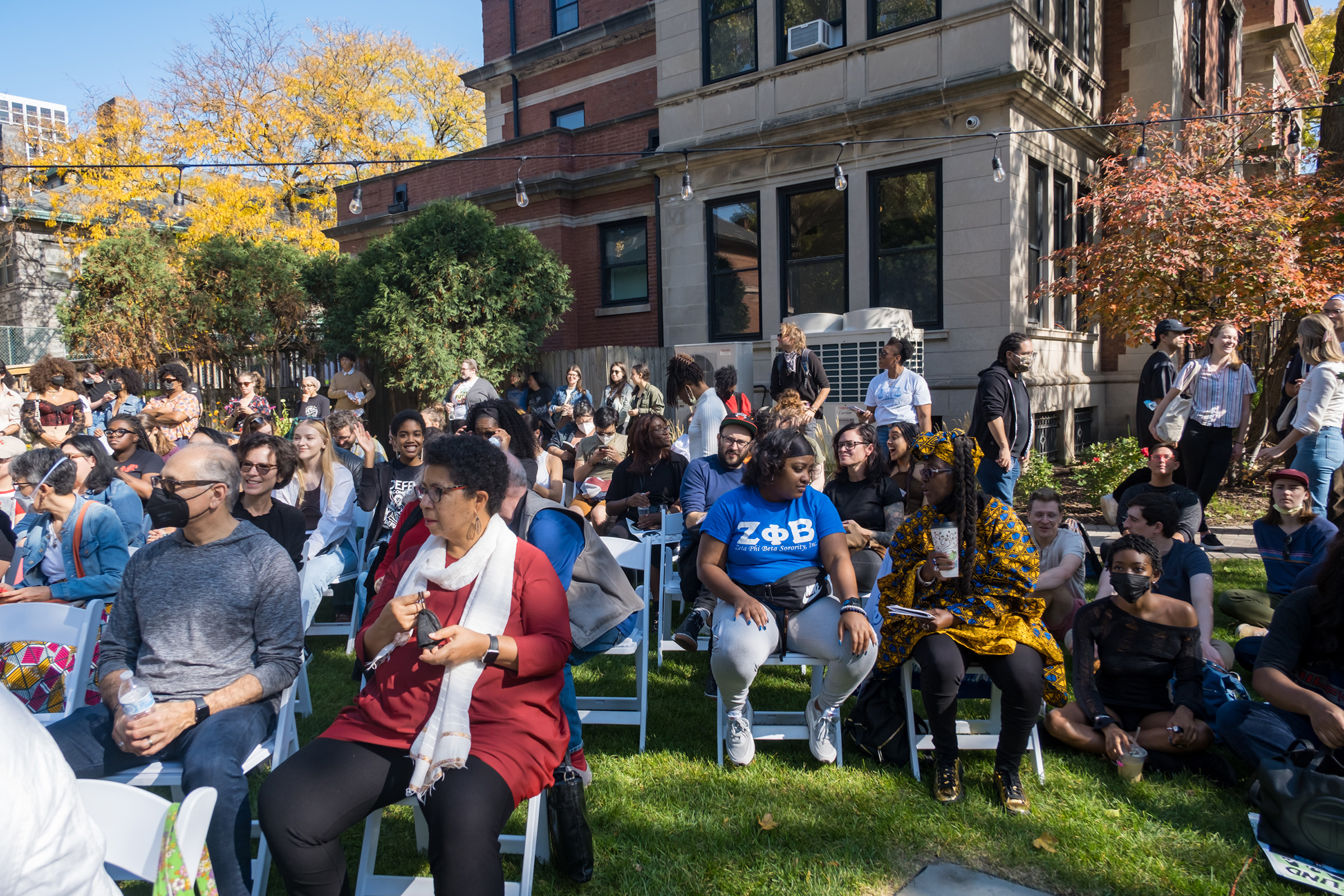 A large group of diverse people sitting on chairs on the Haymarket House lawn.