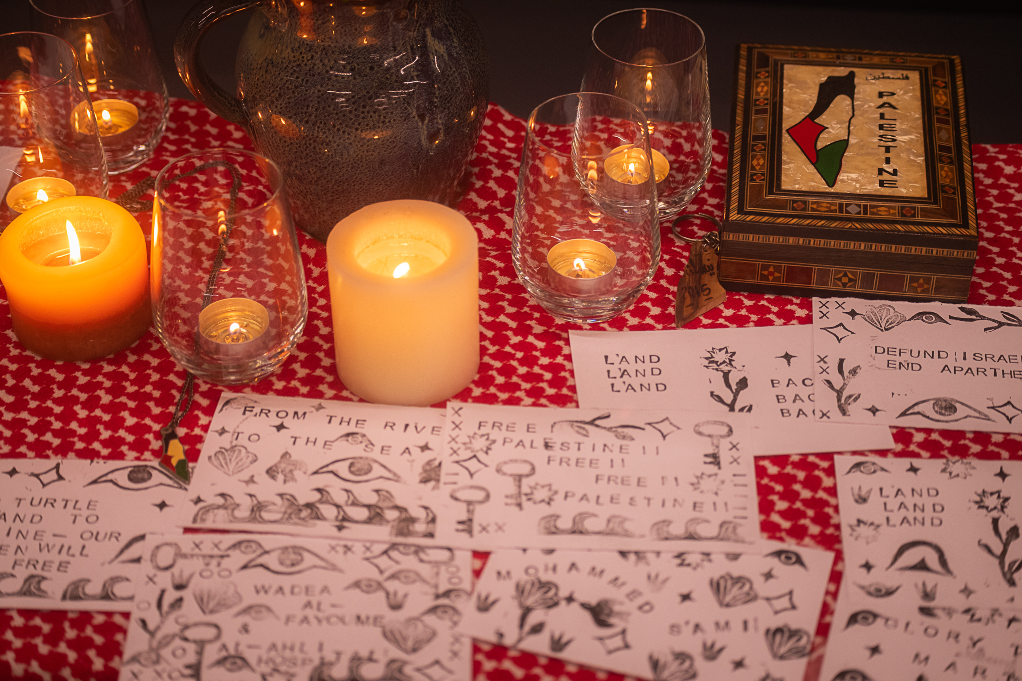 A table with candles and illustrated cards with text about freeing Palestine.