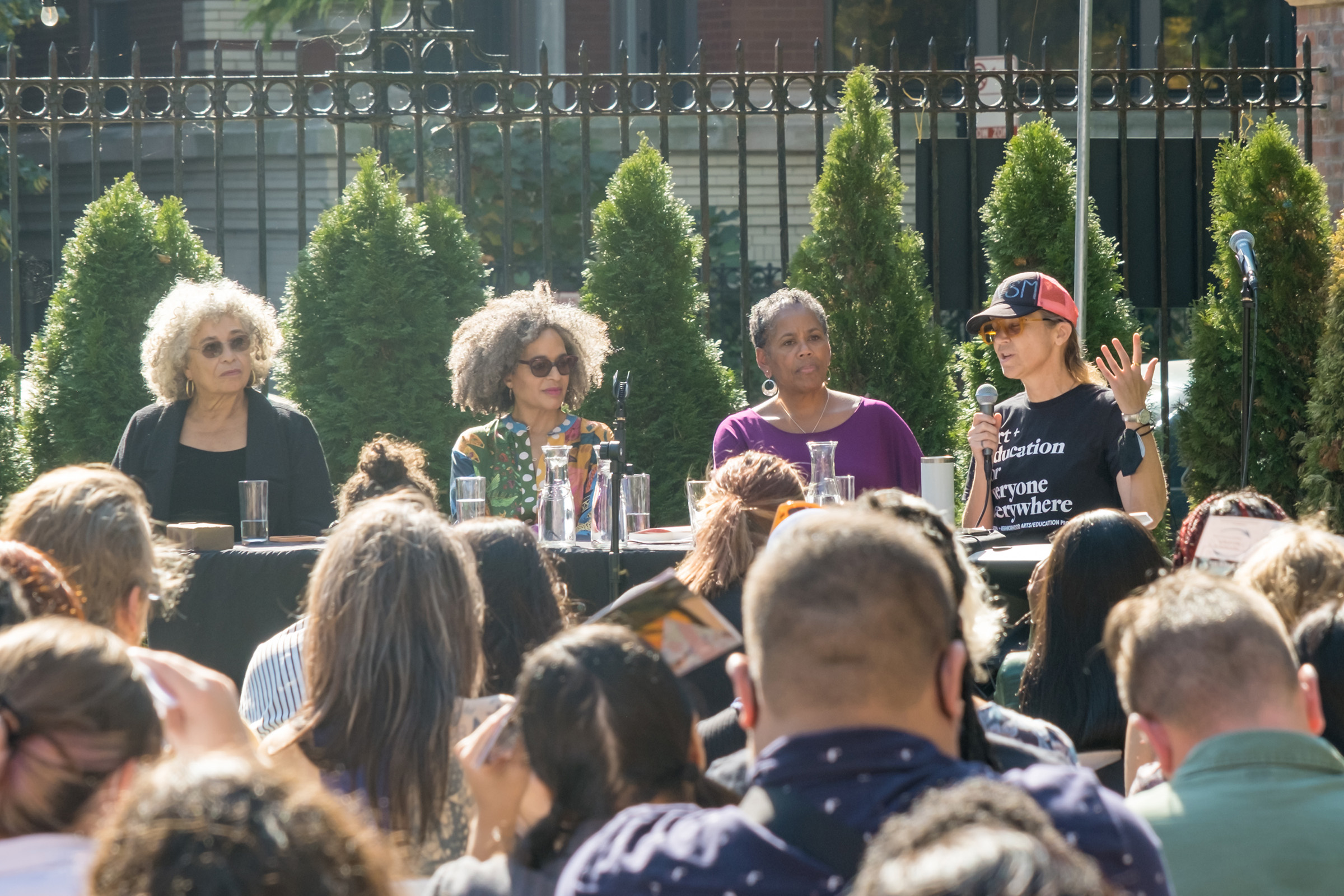 A panel of women speak at an outdoor conference.